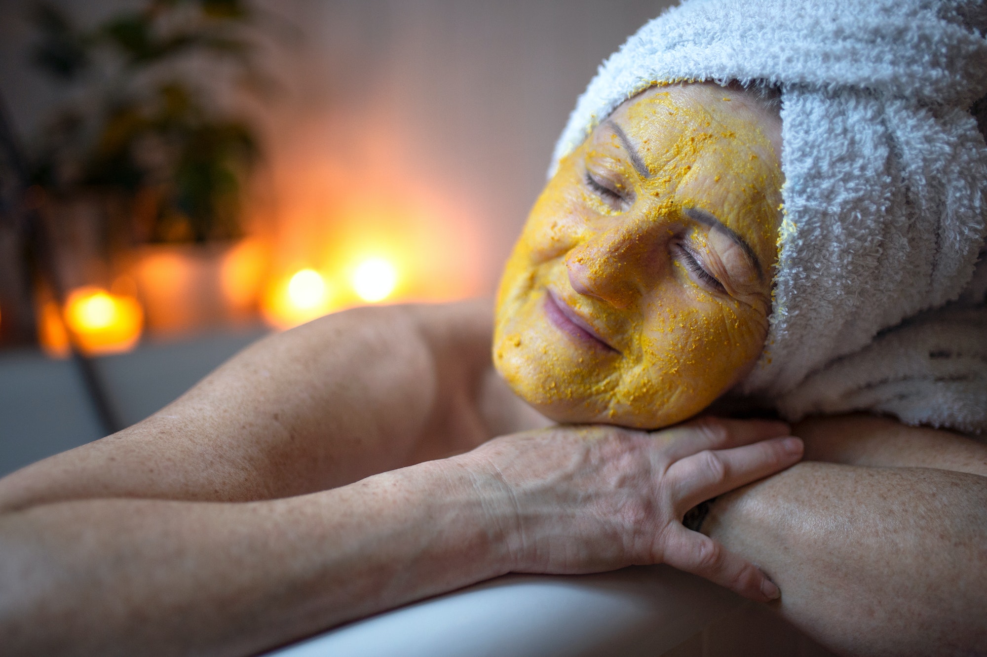 Happy senior woman with beauty face mask in bath tub at home, relaxing
